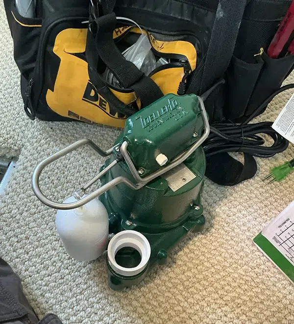 Bell Plumbing technician preparing a Zoeller cast iron sump pump for installation in a Denver, CO home