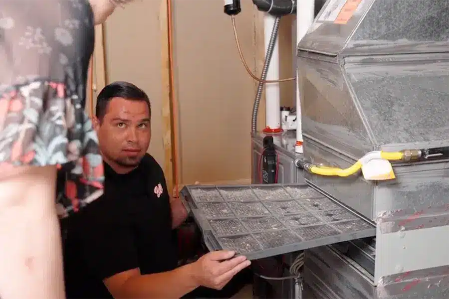 Technician looking at dirty air filter in HVAC unit in Denver, CO.