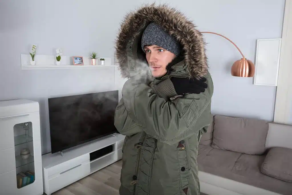 man wearing winter jacket inside house because furnace broke down