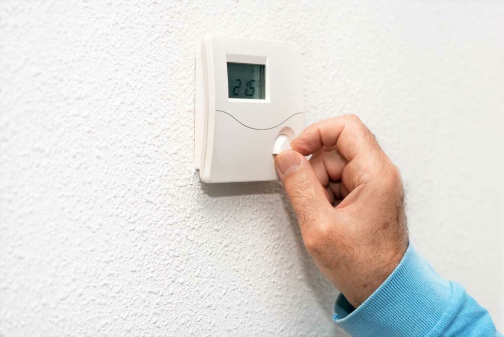 person adjusting thermostat in denver